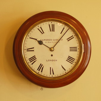 A good 12 inch dial clock in a solid mahogany case . The movement is single fusee has square plates with fine original Steel Hands and runs for 8 days . The enamelled dial is signed by the makers Camerer Cuss and Co , 56 New Oxford Street , London Circa 1890 .The case has two doors - the side door held with a latch and with old labels to the rear of the back box , photos included in the close up pictures . The convex bottom door held with a lock and Key .
