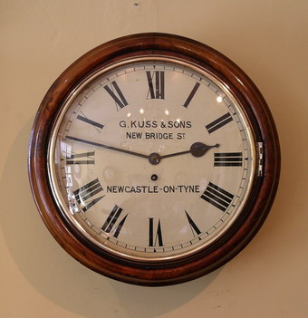 A 12 inch dial clock in a mellow walnut case. The movement is single fusee has square plates with fine original Steel Hands and runs for 8 days . The enamelled dial is signed G.KUSS and Sons of New Bridge Street , Newcastle on Tyne. There are many Kuss family clockmakers recorded working in Newcastle-on-Tyne from as early as 1848 , We would date this clock to around 1890 .The case has two doors - the side door held with a latch and with old repair label and the convex bottom door held with a latch . Please see close up photos by clicking on the image . 